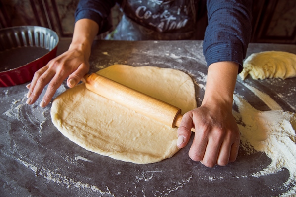 person spreading dough with roller - Пирог печёный из дрожжевого теста