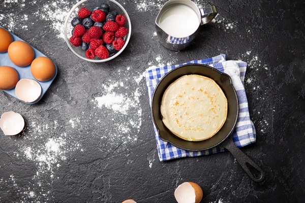 photo on top of eggs milk flour berries on black table ingredients for pancakes - Блинный торт с карамелью и орехами