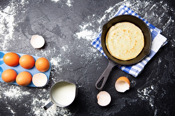 photo on top of eggs milk pan with pancakes towels on black table ingredients for pancakes - Блинчики с мясом