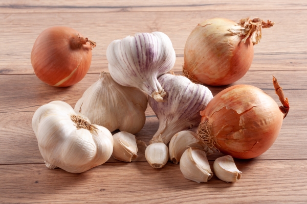 pile of whole onions and garlic bulbs and cloves on a wooden table - Монастырская кухня: перловая каша с овощами, паштет из фасоли