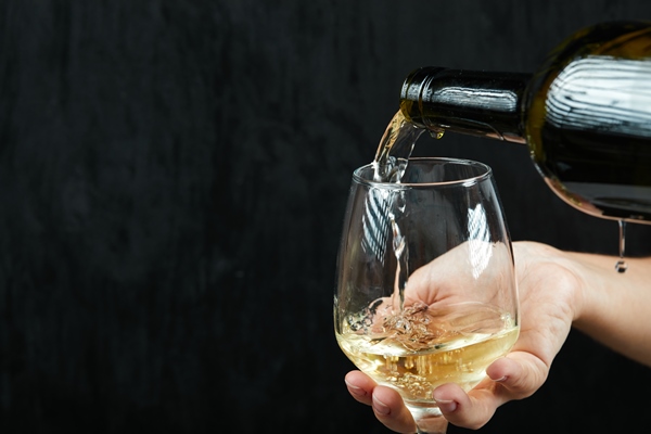 pouring white wine into the wine glass on dark surface - Соус с белым вином к паровой рыбе