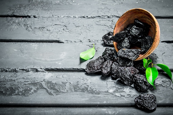 prunes in bowl on black rustic table - Монастырская кухня: тыковник с черносливом и постные оладьи