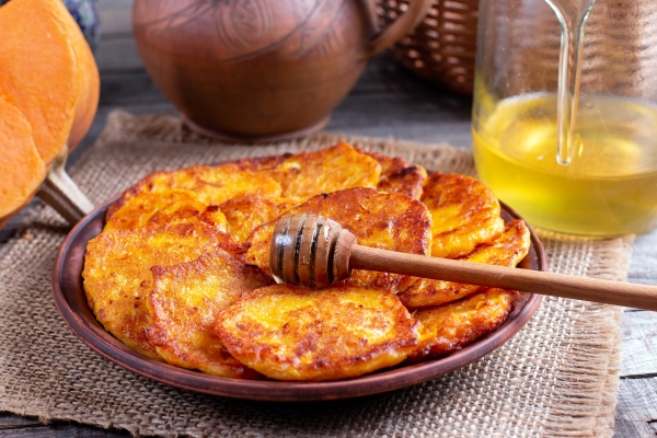 pumpkin pancakes with honey on a plate on a wooden background - Монастырская кухня: луковый суп с редькой, тыквенные оладьи