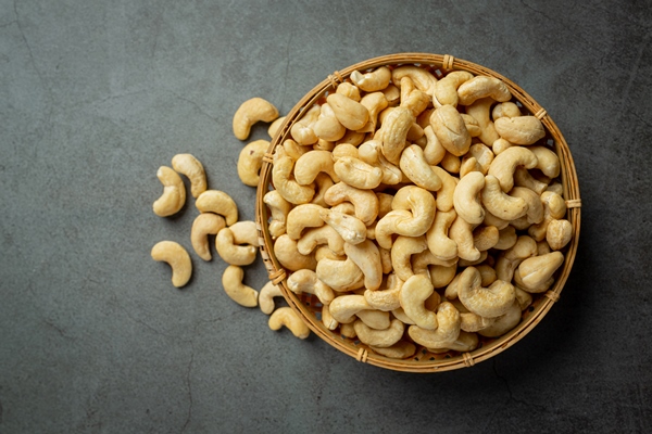 raw cashews nuts in bowl on dark background - Паста из кешью с уксусом и специями