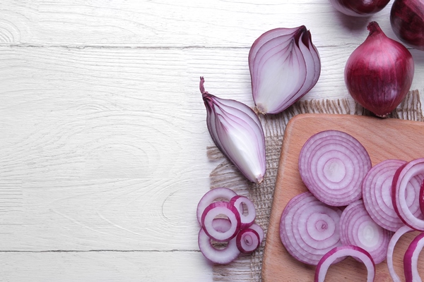 rings sliced red onions and a whole onion on a cutting board on a white wooden table top view - Постные бутерброды с томатами и луком
