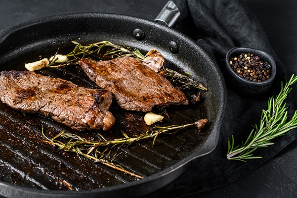 rump steak in a frying pan grilled meat black background top view - Мясо в сметане