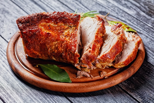 sunday roasted pork tenderloin juicy and succulent oven baked piece of meat rubbed with mustard and spices rosemary bay leaf lime juice and pepper on a wooden background close up top view - Жареная свинина