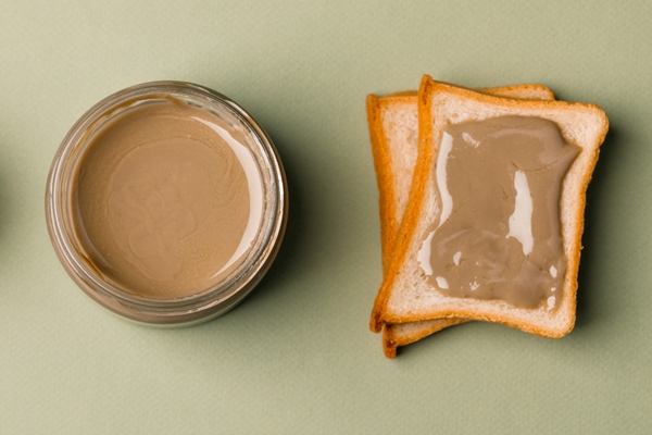 sunflower paste in a small bowl a jar and a piece of bread a modern alternative to nut paste - Паста из грецких орехов и кешью
