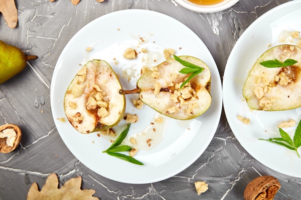 tasty roast pears with honey and walnuts on white plates on grey - Грушевый салат с пеканом