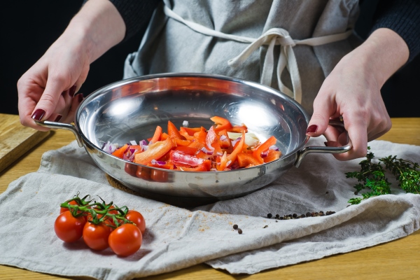 the chef puts chopped red bell peppers and onions with a knife in the pan - Монастырская кухня: тёплый салат из зелёной фасоли и каша-мешанка