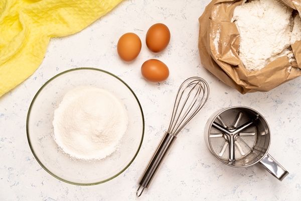 the process of making dough for pancakes with ingredients on a light table eggs and flour are whipped with a mixer 1 1 - Блинный торт с заварным кремом