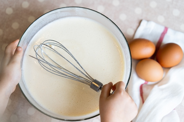 the process of making dough for pancakes with ingredients on a light table eggs and flour are whipped with a mixer 1 3 - Блинчики с яблоками