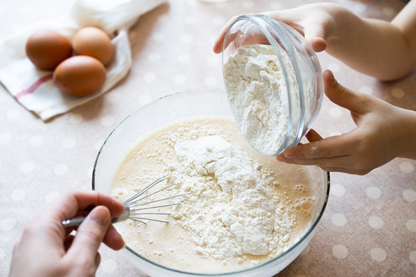 the process of making dough for pancakes with ingredients on a light table eggs and flour are whipped with a mixer 2 - Блинный торт с заварным кремом