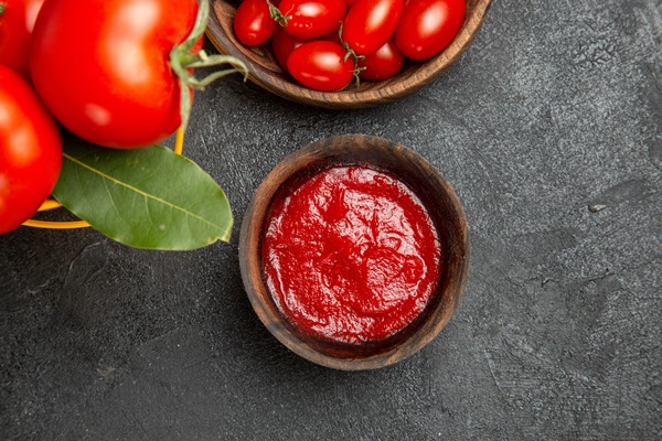 top view a bucket with tomatoes and bay leaves bowls with cherry tomatoes and ketchup on dark ground - Кабачки с мясом