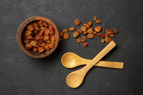 top view dried grape raisins with wooden spoons on dark surface dry fruit raisin - Монастырская кухня: вареники с яблоком и изюмом, морковное печенье