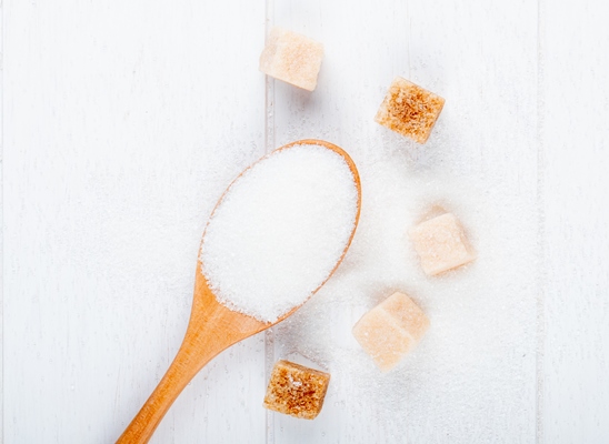 top view of a wooden spoon with white sugar and lump sugar on white background - Монастырская кухня: вареники с яблоком и изюмом, морковное печенье