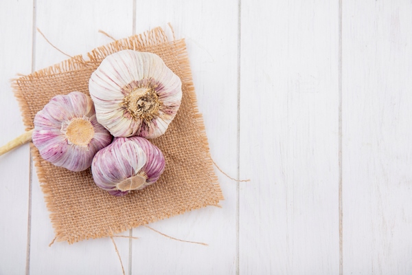 top view of garlic bulbs on sackcloth and wooden surface - Монастырская кухня: овсяная каша, закуска из баклажанов