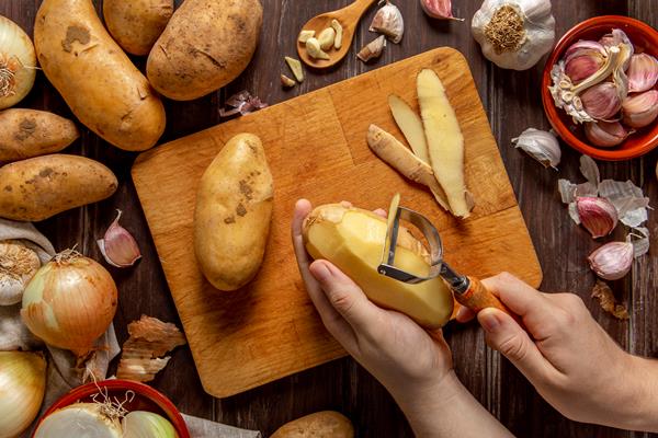 top view of person peeling potatoes - Картофельные блинчики с сыром