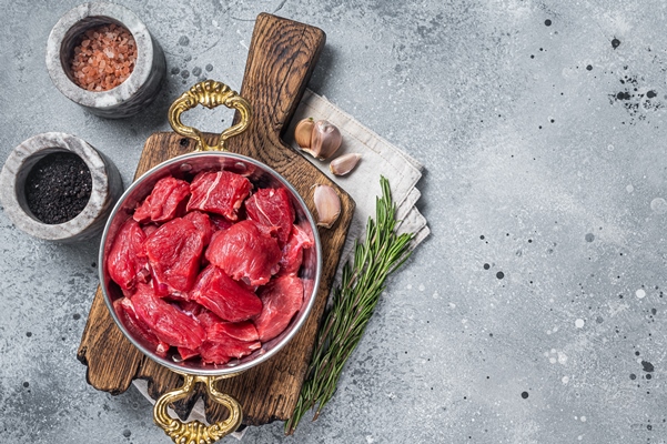 uncooked raw diced beef veal meat for stew in skillet gray background top view copy space - Кабачки с мясом