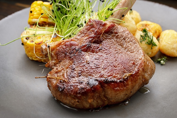 veal entrecote with potatoes and corn on a wooden background - Антрекот с картофелем