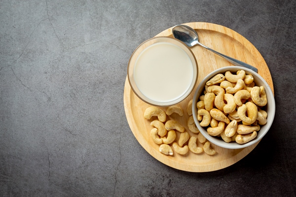 vegan cashew milk in glass with cashews nuts on dark background - Овсянка с бананом без варки