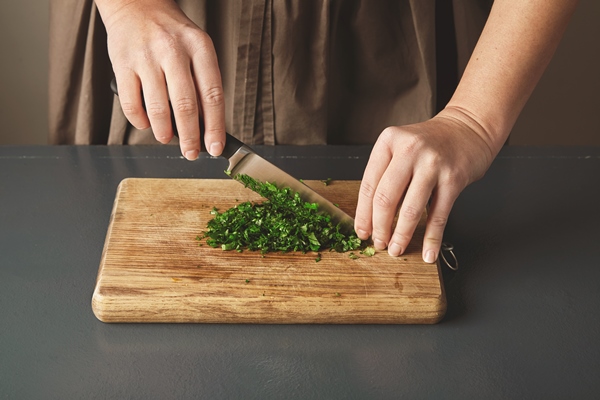 women hand chop parsley on wooden board on old blue table close up - Монастырская кухня: суп "Святогорский", печенье курабье