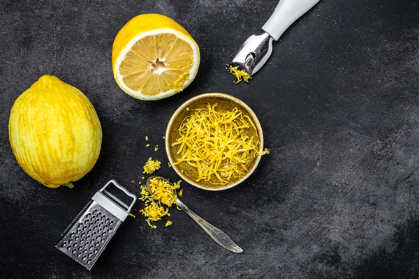 yellow organic lemons zest and special tool grater peel and lemon zest on black background banner menu recipe place for text top view - Морковная бабка