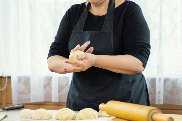 caucasian housewife forms cakes from raw dough on a table sprinkled with flour - Постные луковые лепёшки