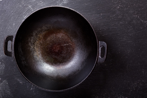 empty wok pan on a dark table top view - Испанское пасхальное печенье "Цветы"