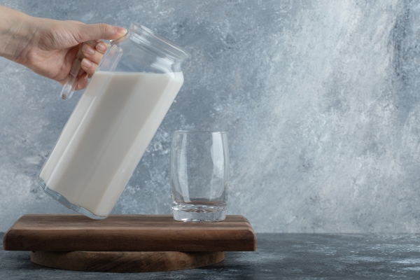 female hands holding jug of milk on marble - Царская пасха без творога с лимонным соком