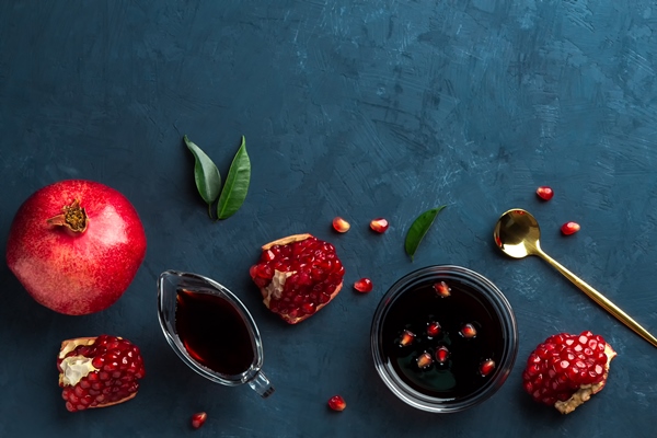 flat lay with pomegranate sauce and pomegranate seeds on dark blue - Рыба под гранатовым соусом