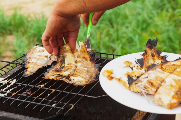 fried fish flounder is on a portable grill - Камбала соте