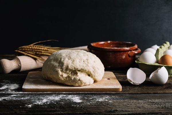 knead dough with ingredients on wooden table - Булочки "Пасхальные зайцы"
