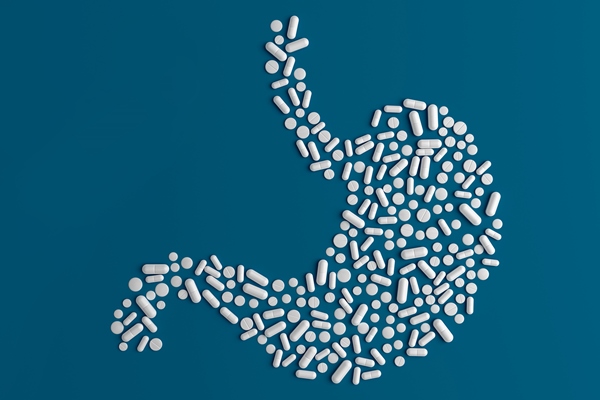 many pills scattered on a blue background in the form of a stomach - Лечебный стол (диета) № 2 по Певзнеру: таблица продуктов и режим питания
