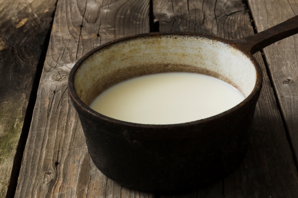 milk in the old vintage saucepan over the old wooden table - Пасха без творога заварная