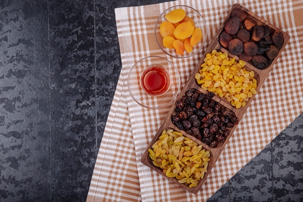 mix of dried fruits raisins cherries and apricots on a wooden tray served with armudu glass of tea on plaid tablecloth with copy space top view - Царская пасха без творога с лимонным соком