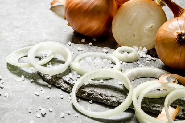 onion cut into rings on a stone stand on grey table - Запечённый красный окунь