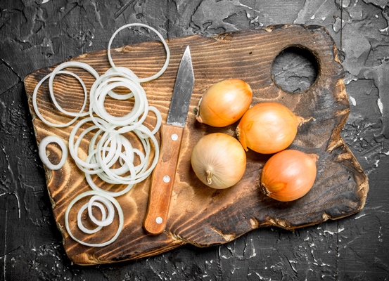 rings of onions on a cutting board with a knife on rustic - Буглама из рыбы