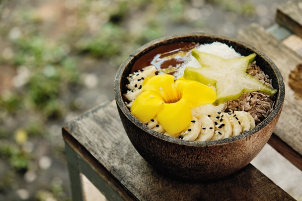 smoothie bowl with tropical fruits carambola bananas decorated with a yellow tropical flower - Лечебное питание