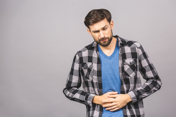 stomach pain or diet problem portrait of sick handsome young bearded man in casual standing and holding his painful belly feeling bad isolated on grey gray wall wall - Лечебное питание
