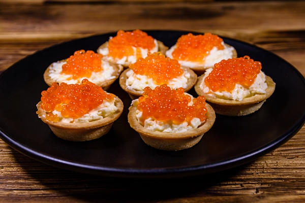 tartlets with red caviar on a black plate festive food - Постный салат с кальмарами, икрой и креветками