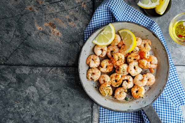 tasty appetizing fried shrimps on pan on dark stone background top view - Постный салат с кальмарами, икрой и креветками