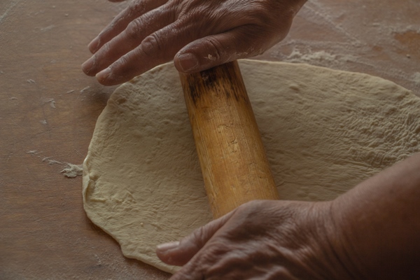 the process of rolling yeast dough on a wooden board - Пирог с икрой