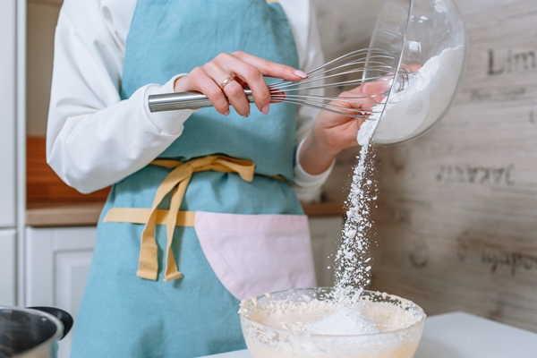 the woman cook adds flour to the dough the process of mixing cake ingredients in the home kitchen 1 - Куличи александрийские