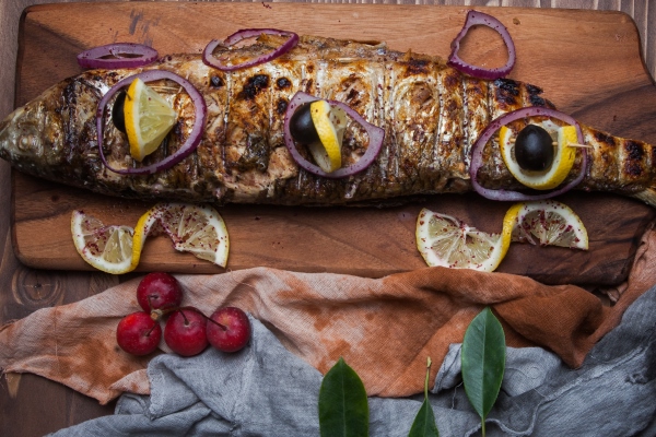 top view fried fish with lemon and paradise apples and onion in cutting board - Скумбрия, запечённая с яблоками