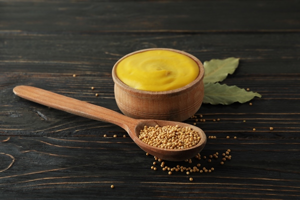 bowl with mustard and spoon with seeds on wooden background - Салатный соус из черемши