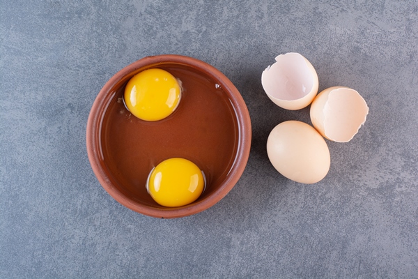 clay bowl of egg yolk placed on stone table - Запеканка с лебедой
