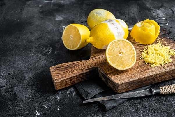 grated lemon zest and spiral peel on wooden board black background top view copy space - Квас из одуванчиков