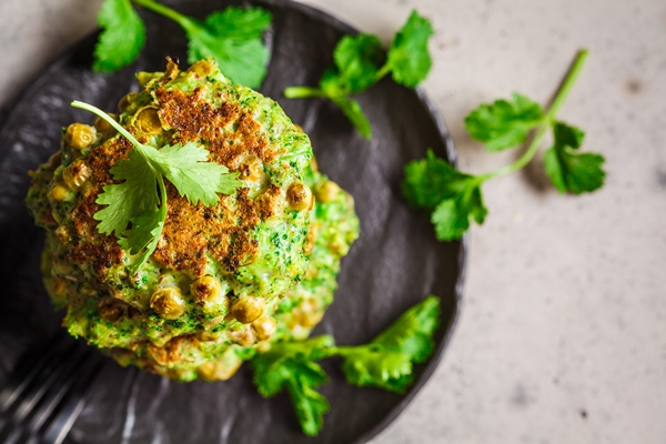 green broccoli and pea pancakes on black plate top view healthy vegan food concept - Биточки из сныти