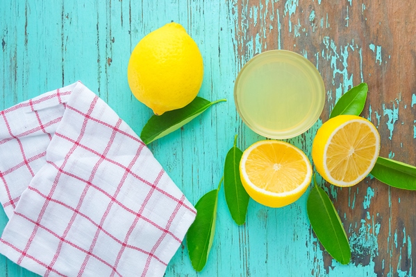 half lemon and lemon juice squeeze in a small cup place on an old green wooden table - Паштет из черемши с томатами